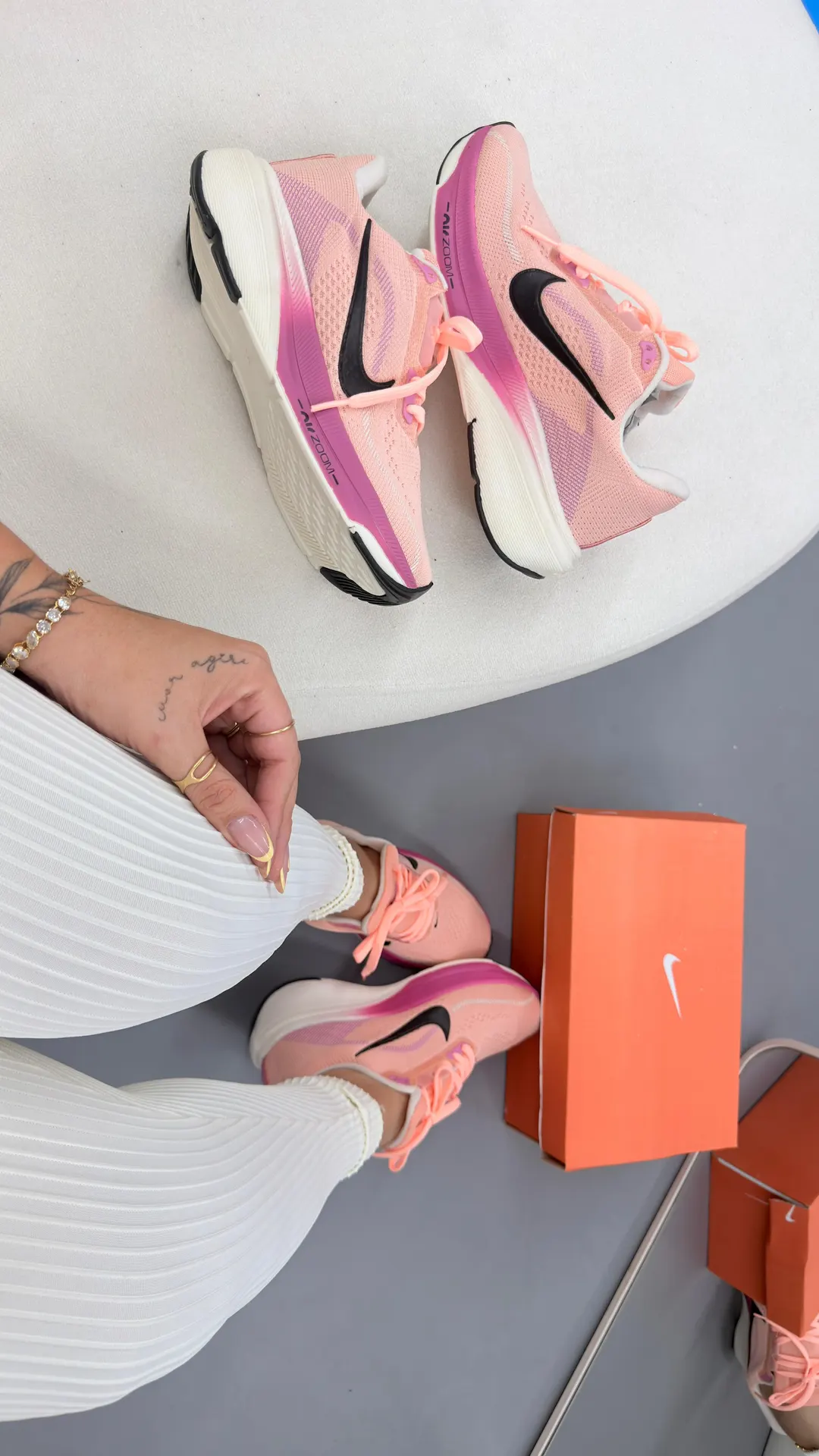 Tênis de corrida rosa claro com entressola branca e detalhes em pink