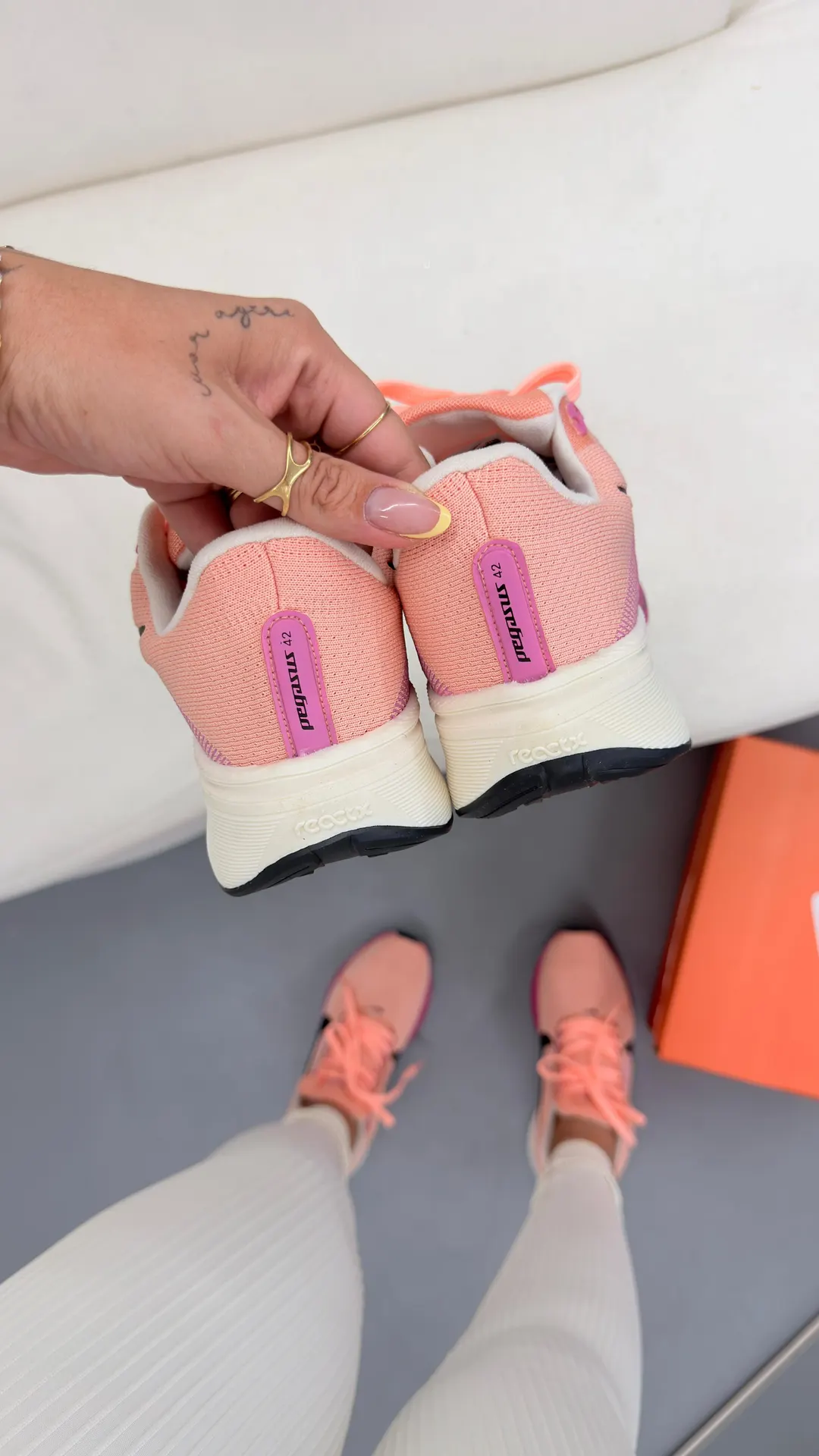 Tênis de corrida rosa claro com entressola branca e detalhes em pink